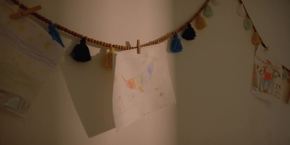 Childs drawings hang from beaded and tasseled cords