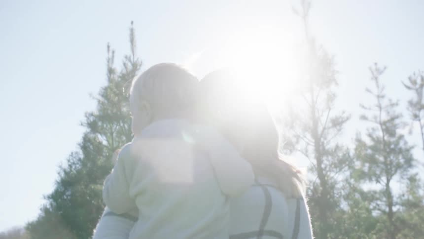 A woman is carrying her child in the forest