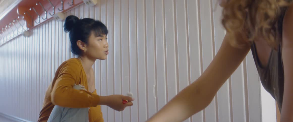 Two women repaint white paneling on a wall