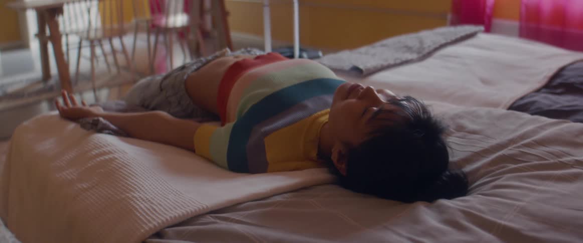 Woman lies back on bed with smile in one room loft