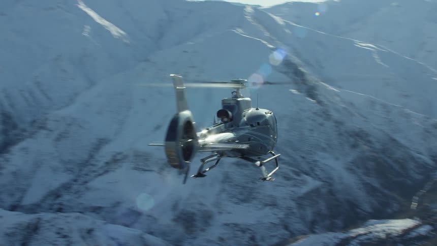 Aerial view of a helipopter hovering over a snow covered mountain range