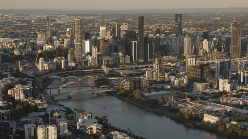 Boats travel on the river of a large city with skyscrapers and bridges