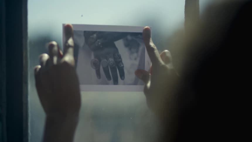 A person in a room placing a photograph on a window