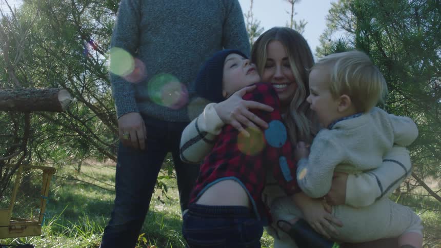 A family of four stand by a cut down christmas tree in a forest area
