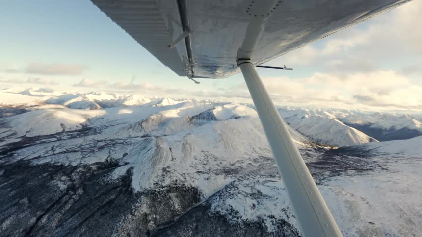 View outside under a plane wing that is flying