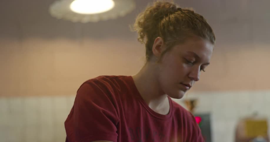 Woman with a pony tail and wearing a red shirt moves items from one spot to another