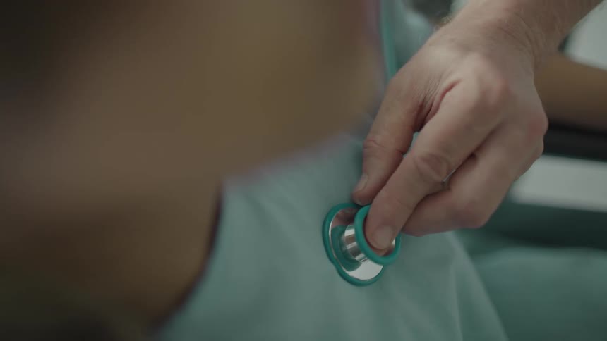A doctor checks a patients heart with a stethoscope
