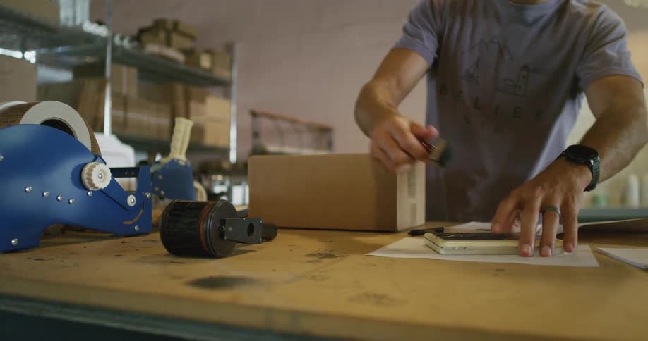 An employee prepares a box for shipping