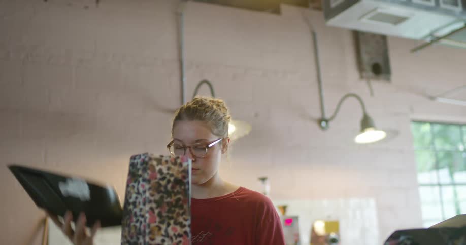 Woman packing coffee beans on a colorful bag inside a warehouse