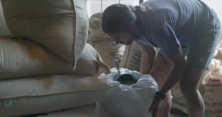 A man scooping grain from a large burlap sack