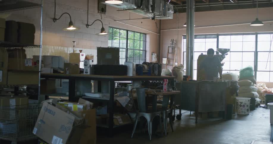 Man organizing papers over a desk inside a small warehouse