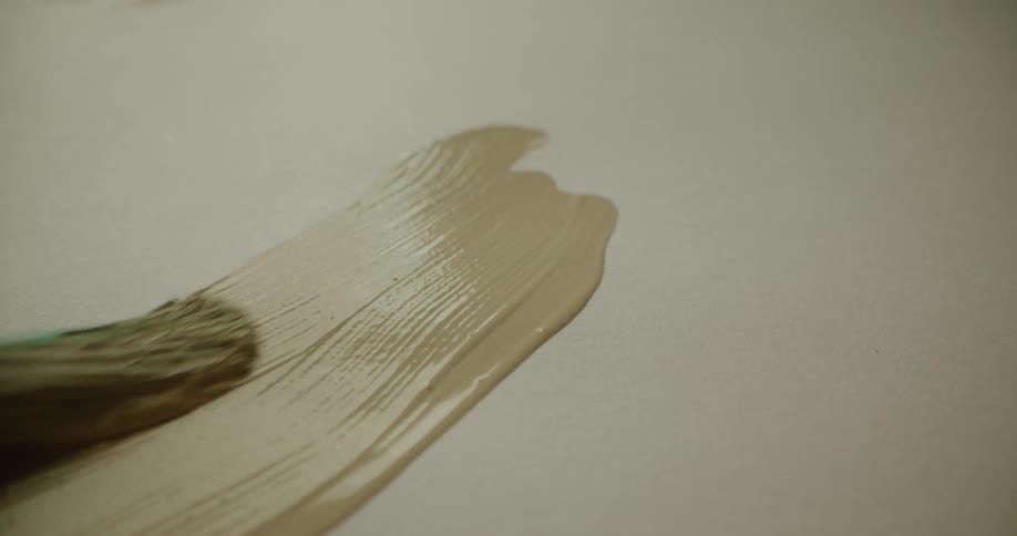 A paint brush applies paint strokes onto a blank canvas