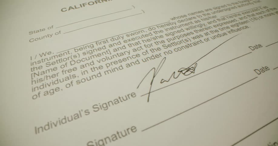 A pen signing a signature on a paper on a desk