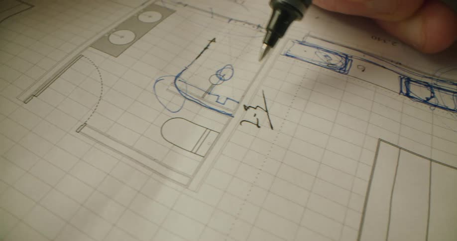 A close up of a person drawing on engineering paper