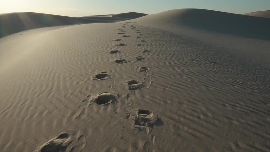Footprints in a sand dune on a sunny day