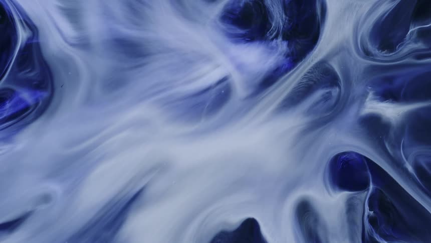 Swirls of white and blue smoke move around in the dark