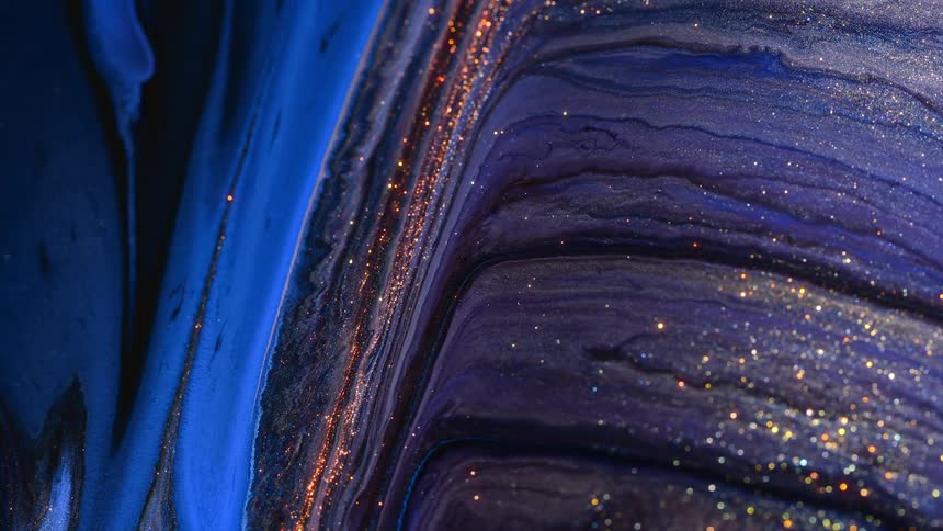 Gold glitter rises from purple liquid and liquid flows down
