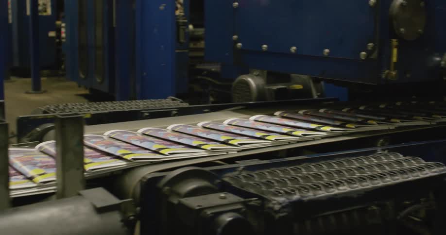 Large machine lays newspapers on conveyor belt