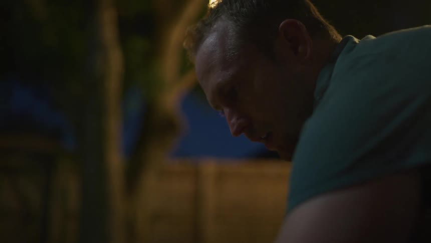Man gets ready to put up a tent in the yard at night