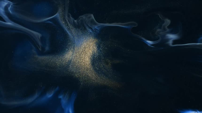 Gold particles shine at center of spreading swirling blue and black mixture