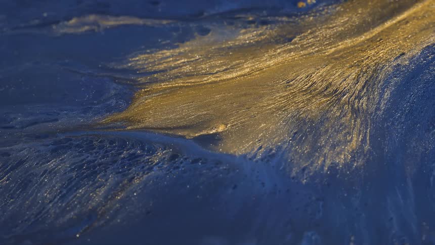 A wave of blue gold and black colors that look like sand and water and rotate