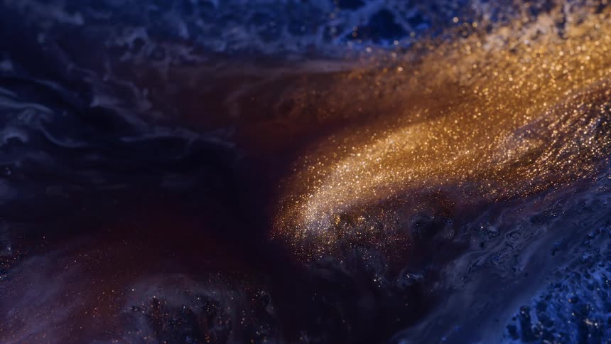 Gold glitter shimmers as it slides across a blue textured surface