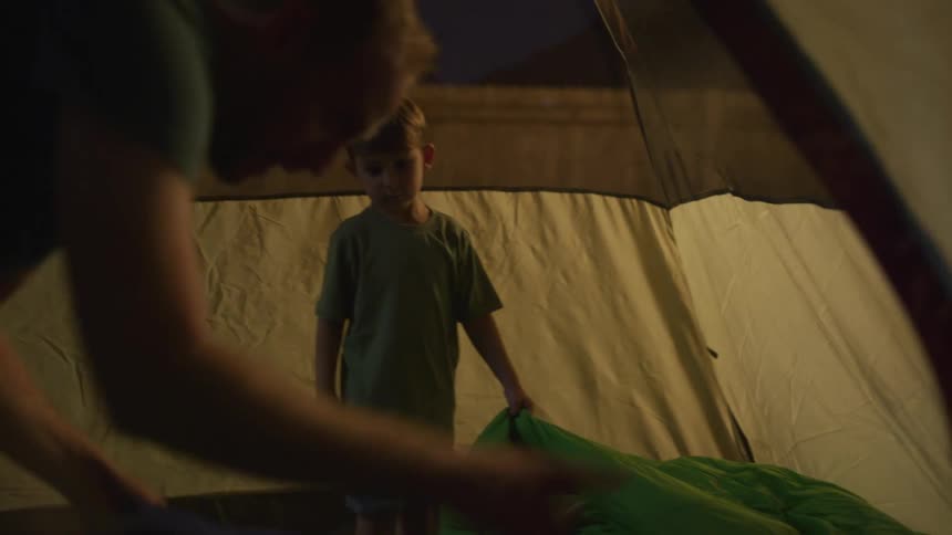 Father and son camping on a tent in the backyard at night
