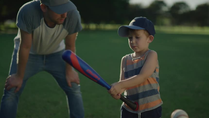 A child and father playing tee ball outdoors