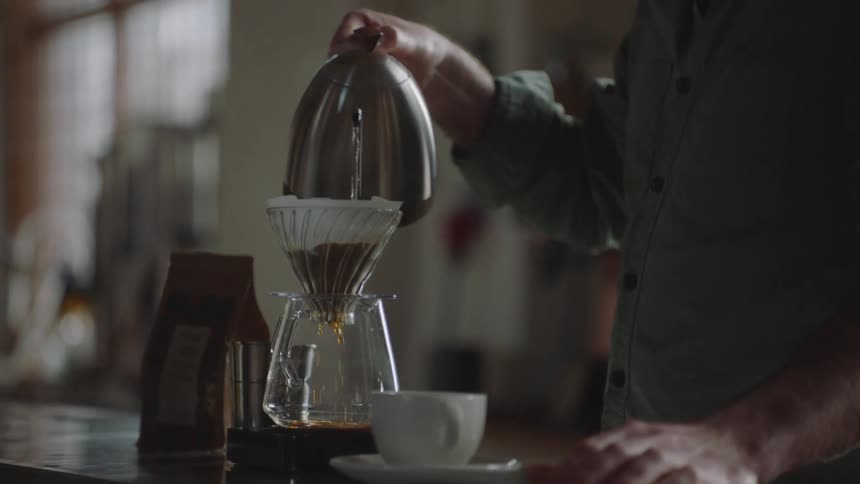An employee makes a pour over coffee in a cafe