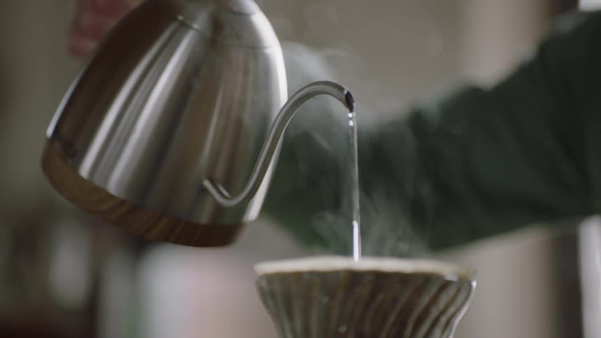 A person pouring hot water into coffee grounds