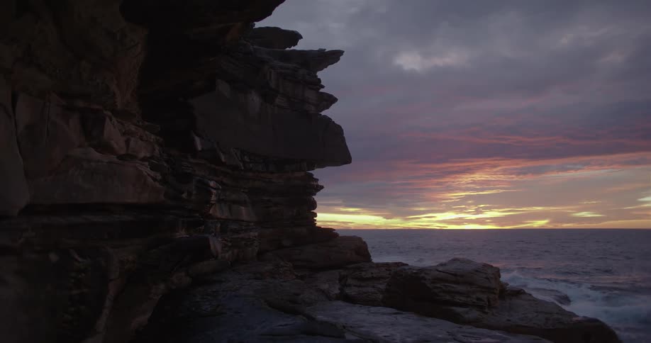 A rocky cliff on a beach at sunset