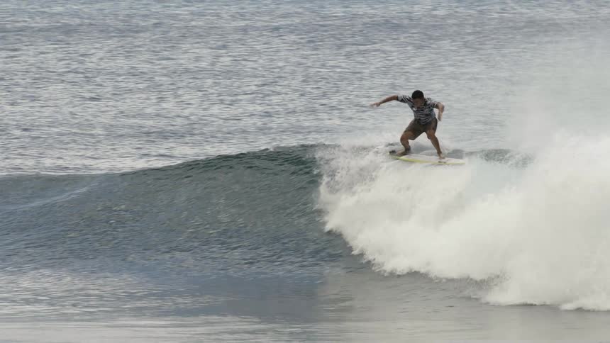 A male surfer riding an ocean wave in summer