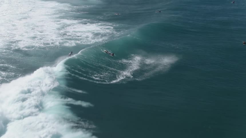 A surfer in Hawaii throws spray off of the back of a wave