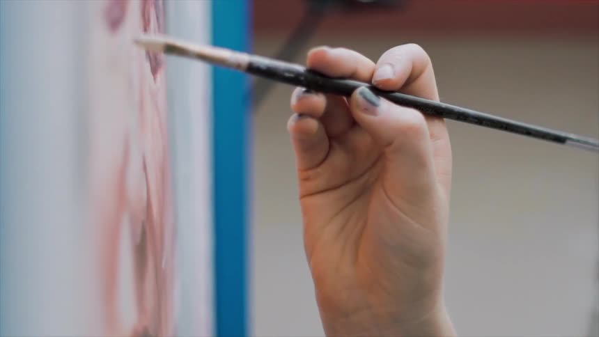 A hand is painting a portrait