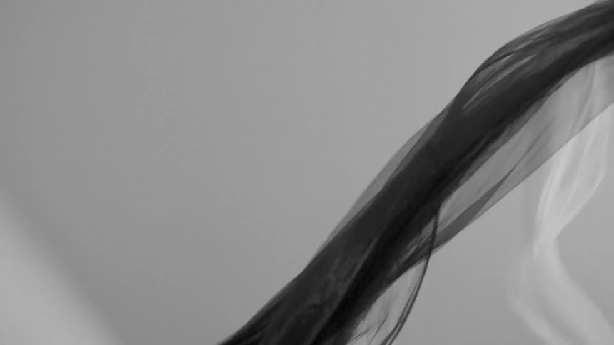 A gray sheet and a white sheet billows in the wind
