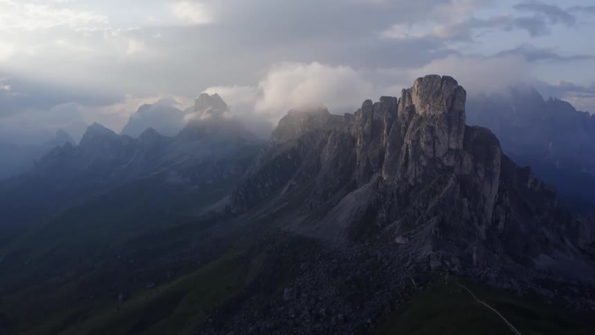 Clouds floating above steep mountains in the daytime