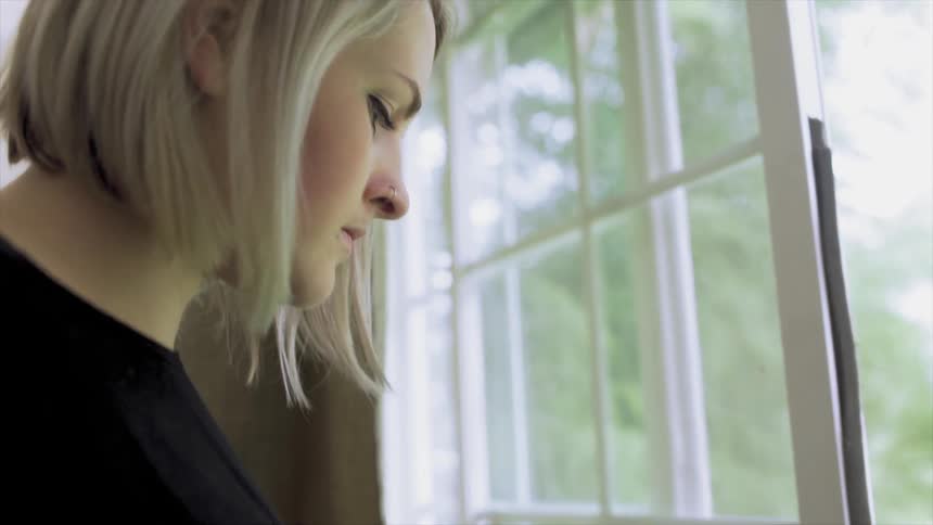 A blond woman inspects a paint brush