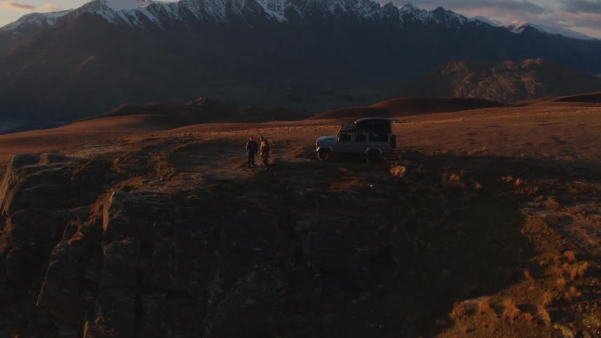 An aerial shot of a car on a cliff