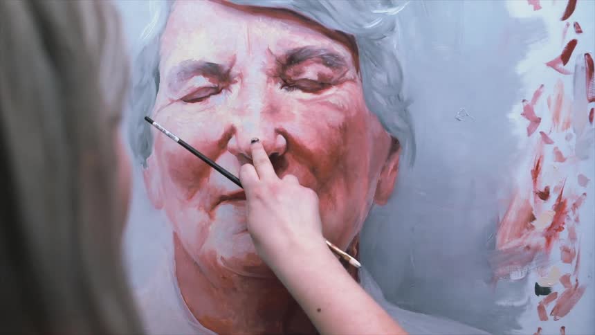 A woman is painting a portrait of someone