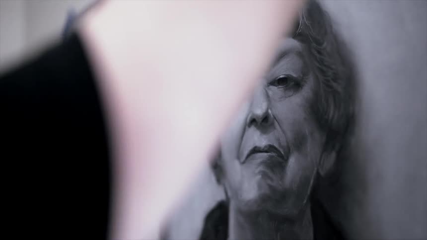 A person hangs up a picture of an elderly lady on the wall