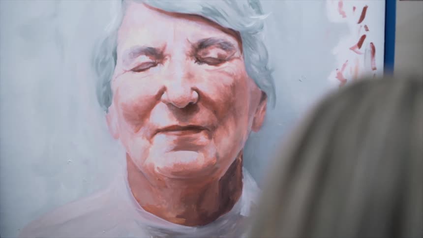 A woman is working on a portrait