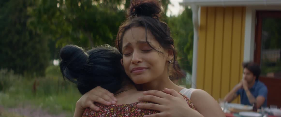 Two women smiling and hugging each other outside in summer