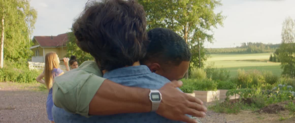 A pair of men greet each other at an outdoor get together during the day