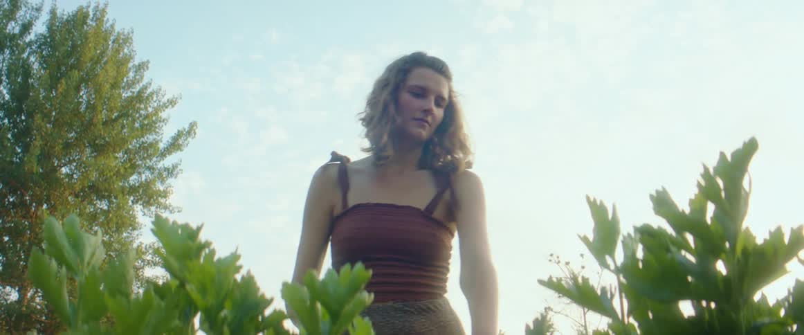 A woman is holding a water can over several plants