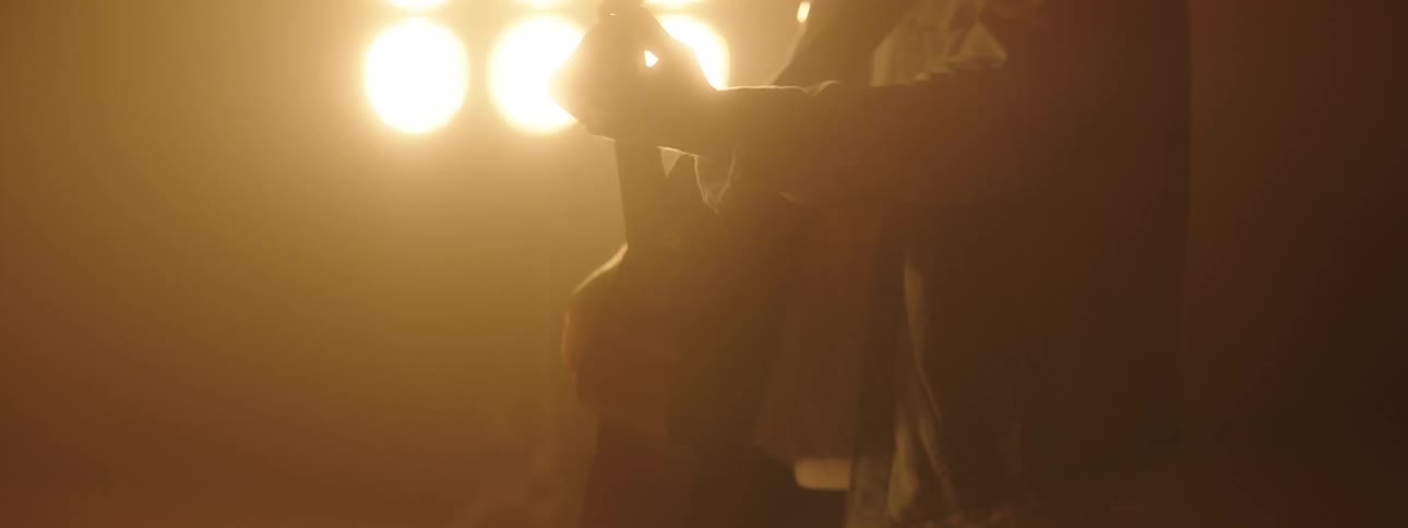 A man plays guitar on a stage with bright lights