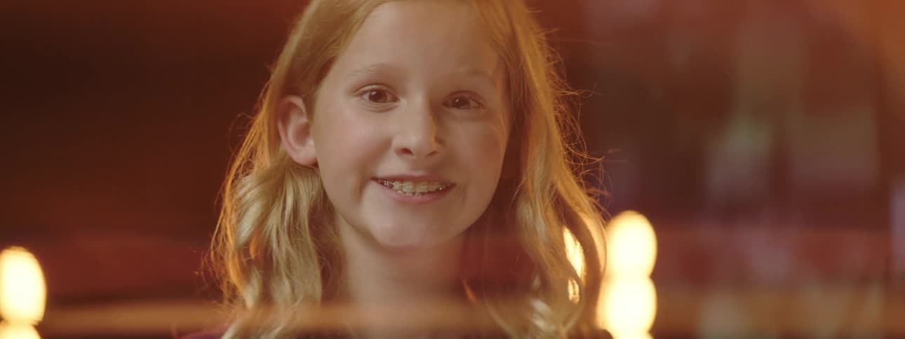 Lights glow behind a little girl smiling