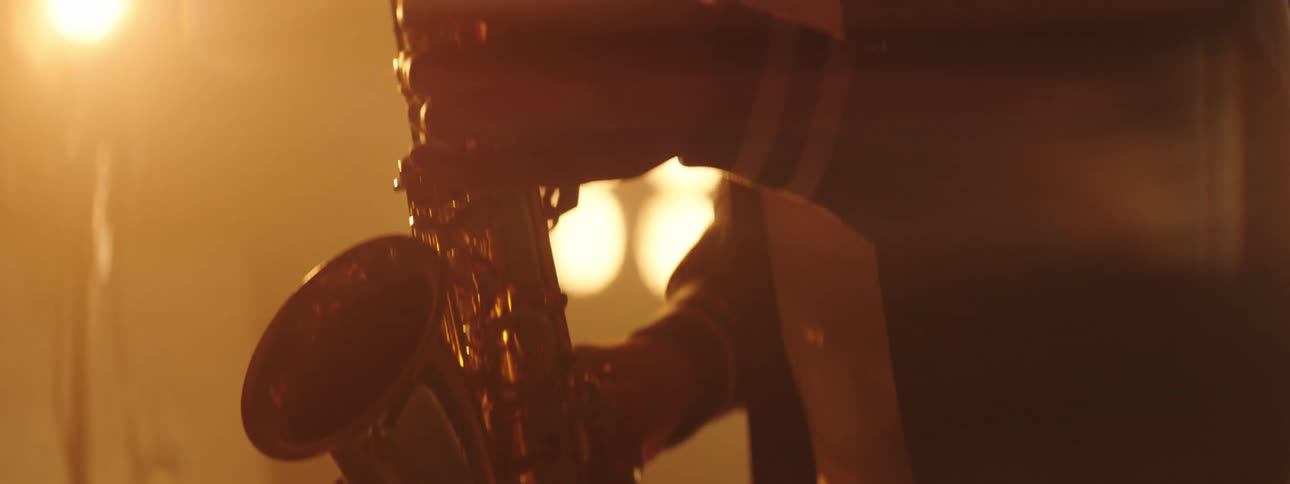 A man sways back and forth while playing a saxophone on stage