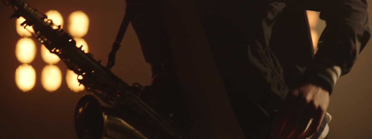 Bright lights shine on a man playing a saxophone