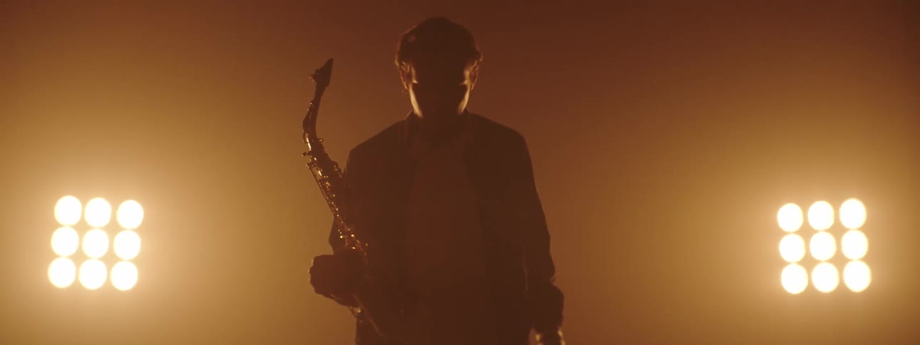 A man walking onto a stage with a saxophone