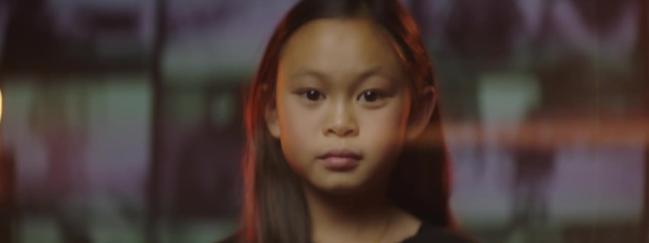 A portrait of a girl on a stage with screens behind her